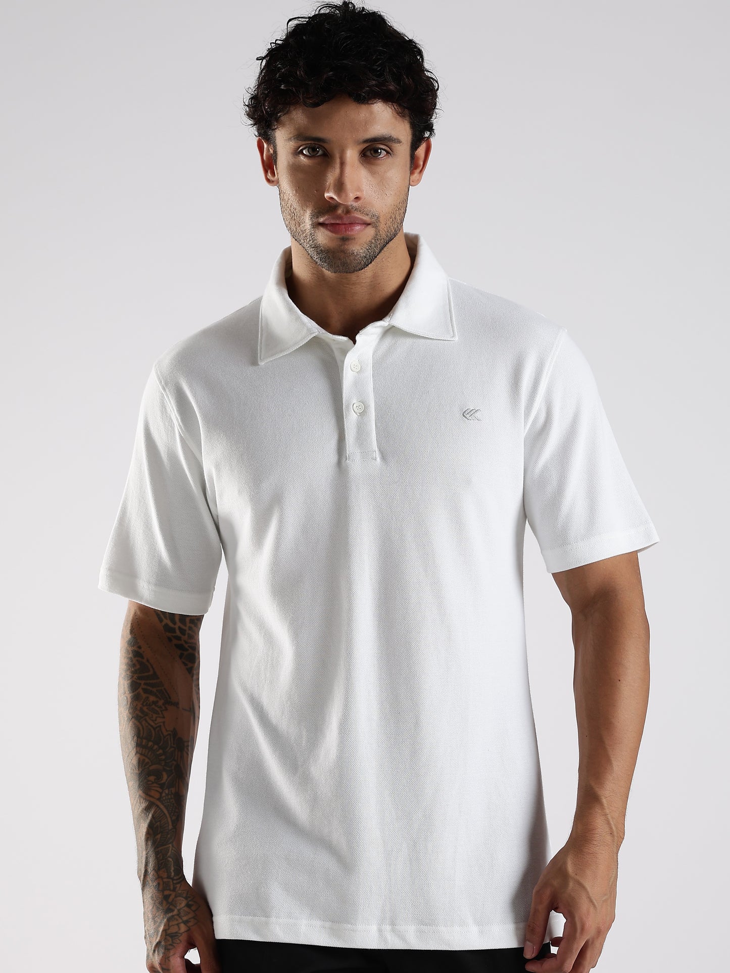 Man wearing a Soft white polo shirt with a brand logo on a light gray background