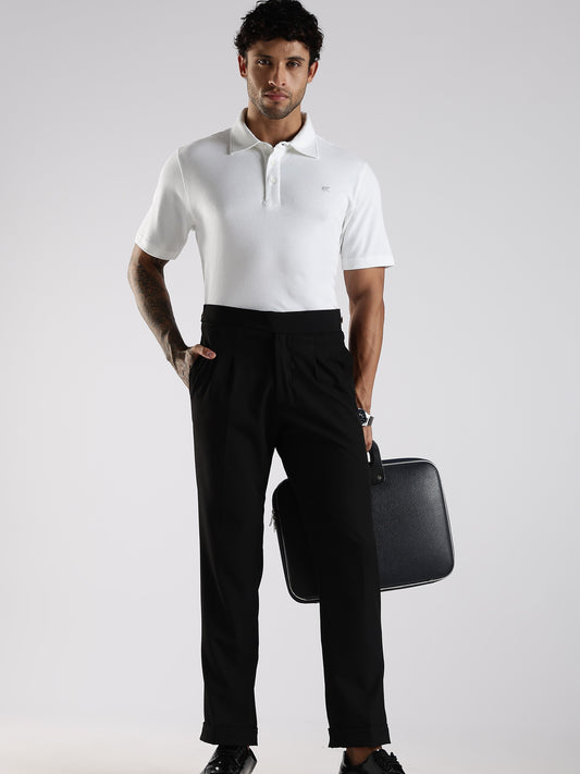 Man wearing a white polo shirt and black pants holding a black briefcase on a light gray background