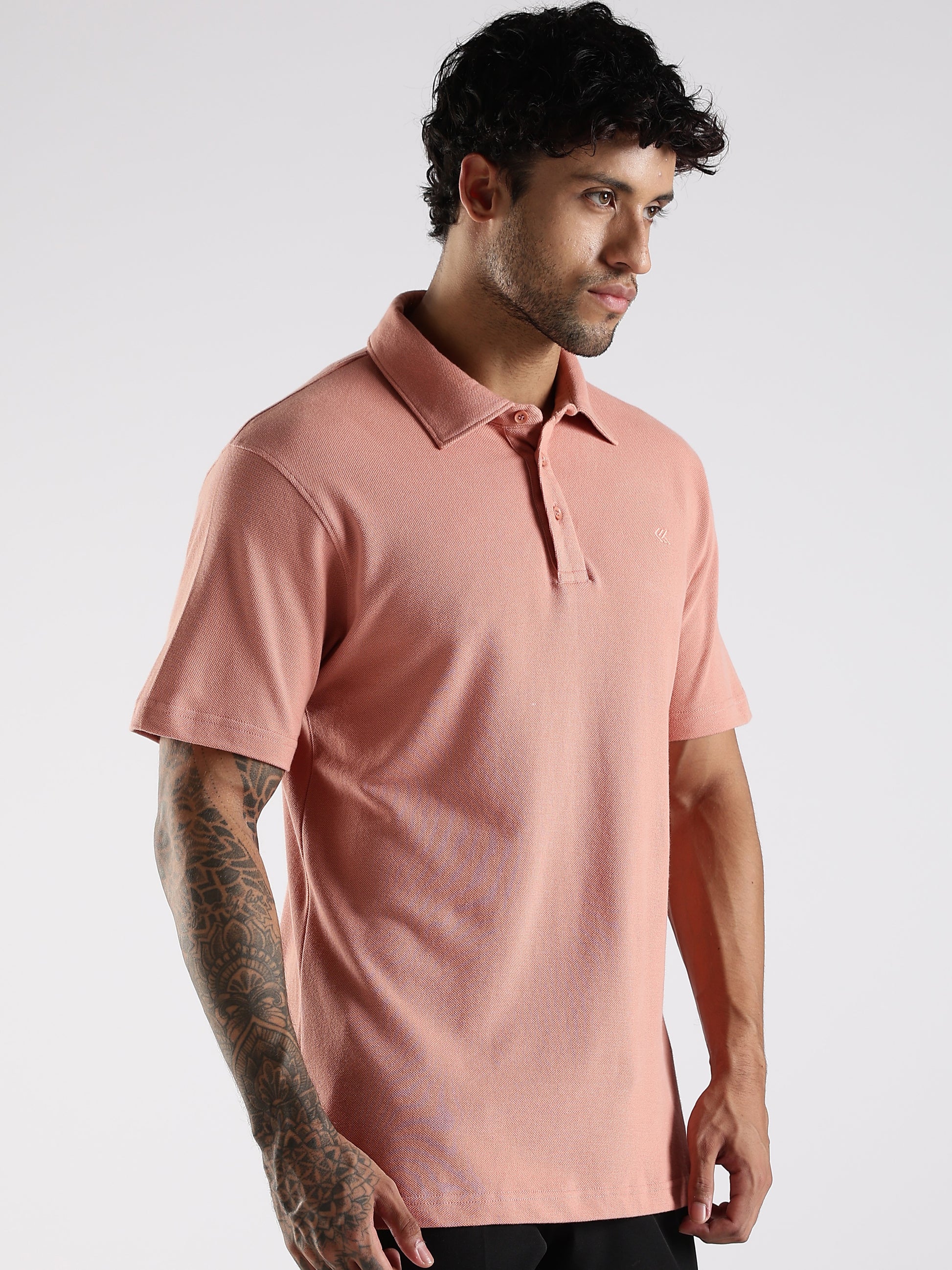 Male model showcasing a peach solid polo shirt in cotton, designed with a professional fused collar for versatile wear.
