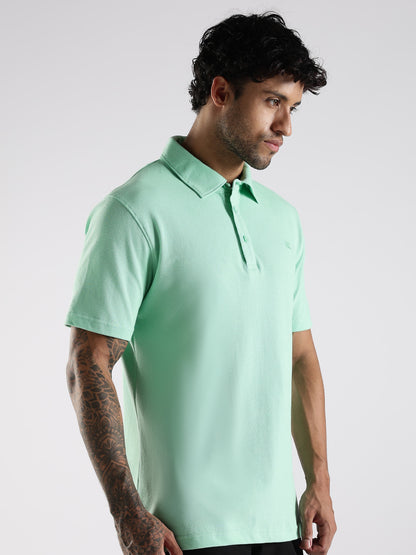 Side profile of a male model wearing a sea green cotton polo, showcasing its tailored shirt-style collar with stand.