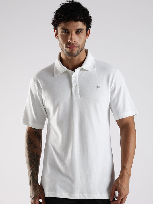 Man wearing a Soft white polo shirt with a brand logo on a light gray background