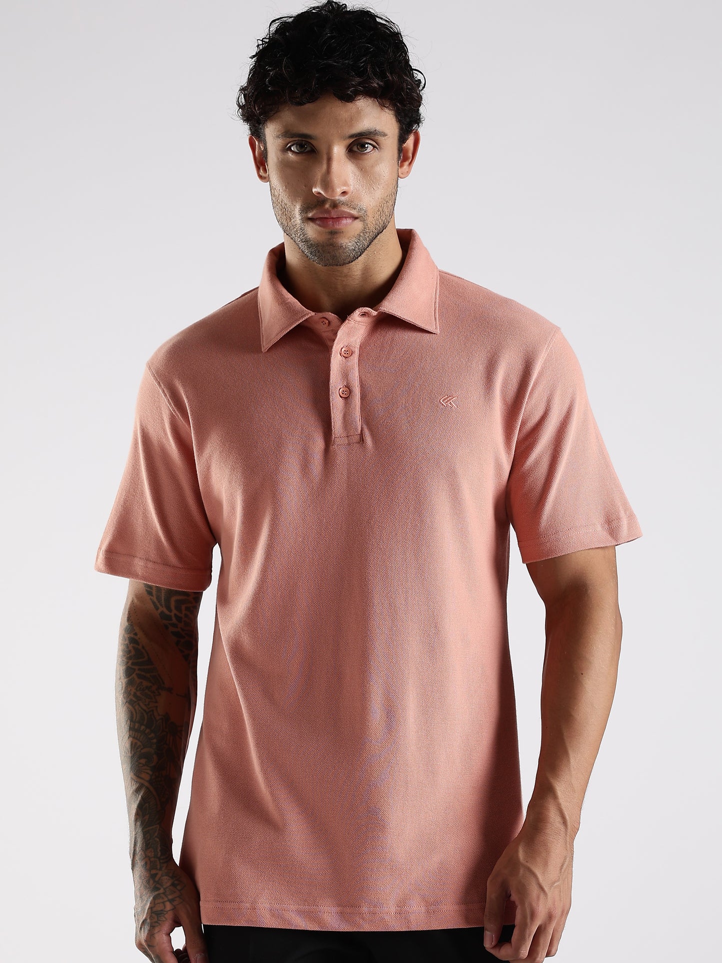 Man wearing a pink polo shirt against a white background