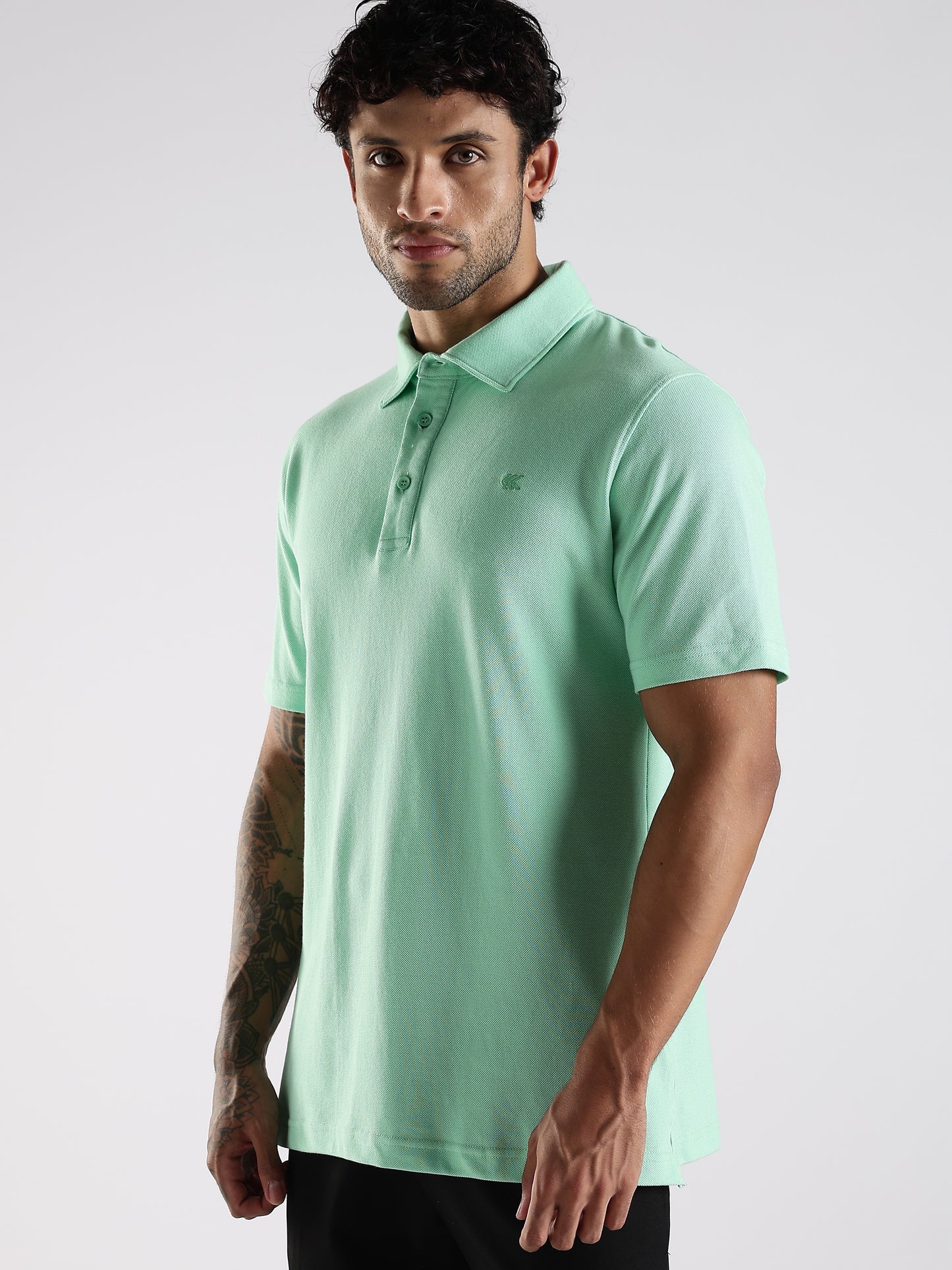 Model posing in a sea green 100% cotton polo with a structured collar stand, styled for a smart casual appearance.
