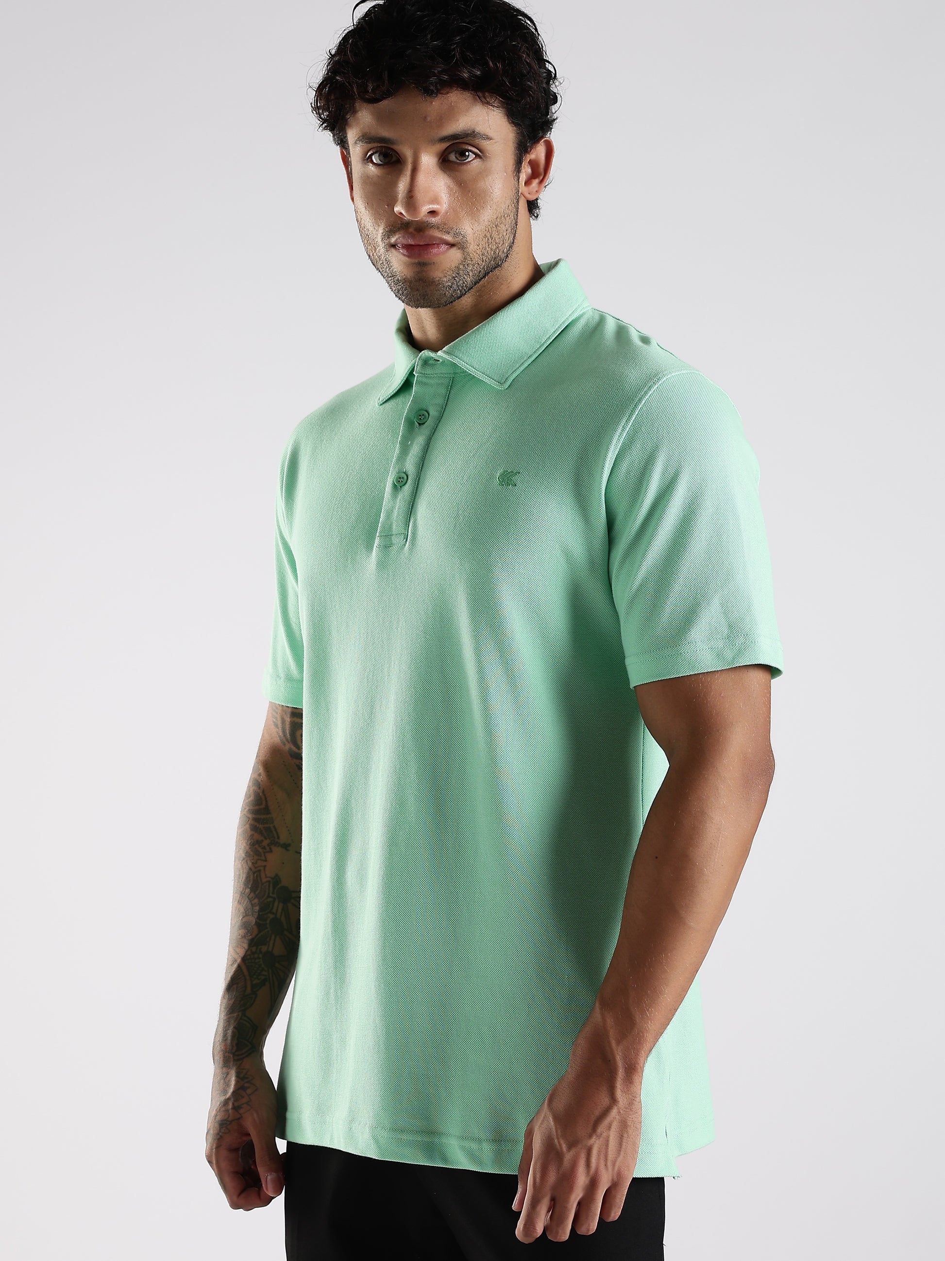 Model posing in a sea green 100% cotton polo with a structured collar stand, styled for a smart casual appearance.