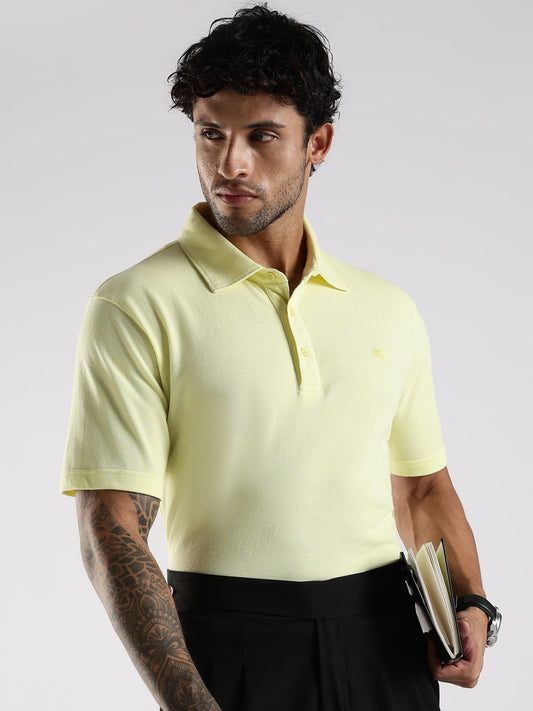 Man wearing a light yellow polo shirt against a white background.