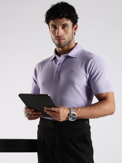 Man wearing a light purple polo shirt styled with black pant holding a tablet against a white background