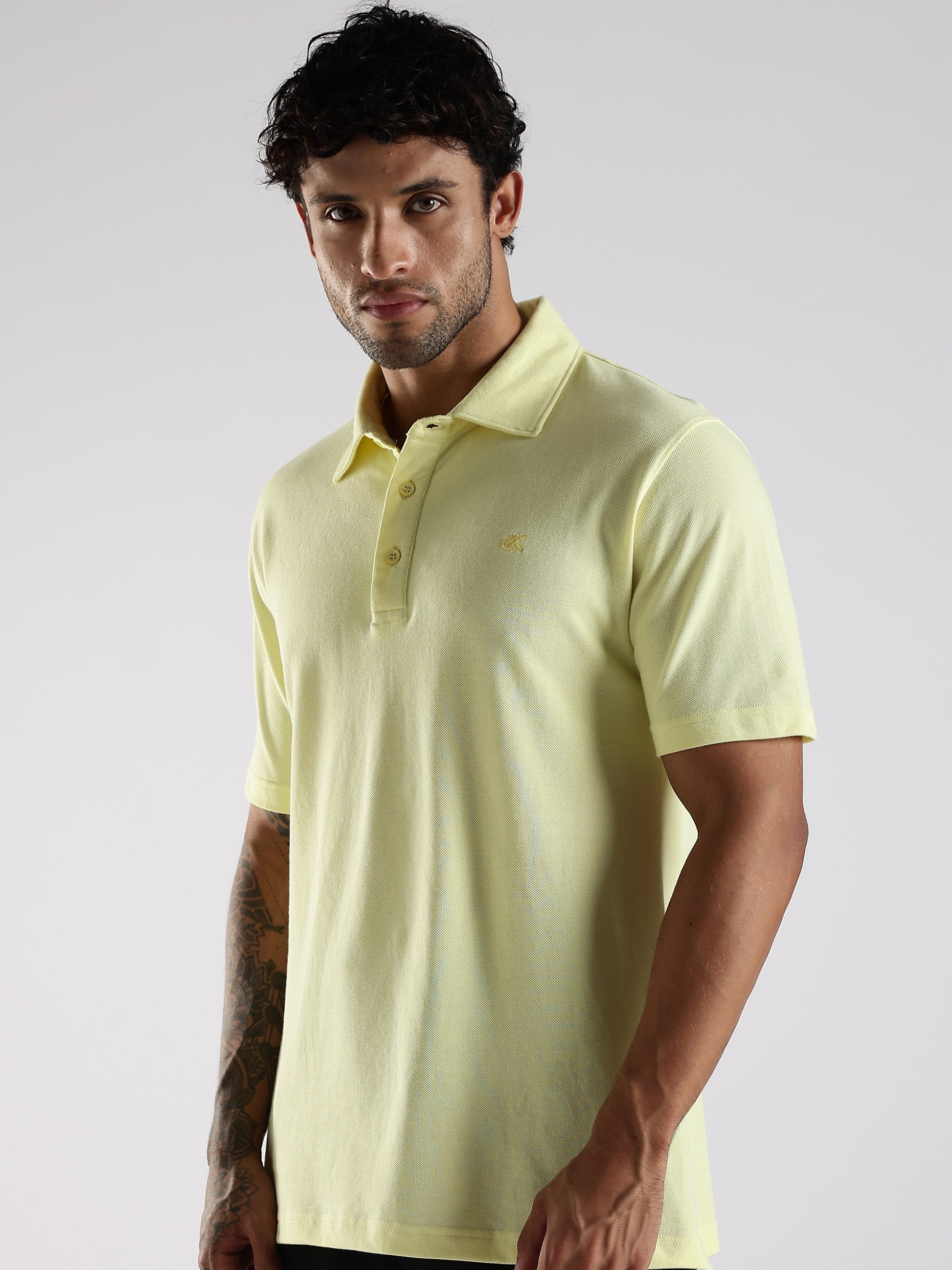 Man wearing a light yellow polo shirt against a plain background