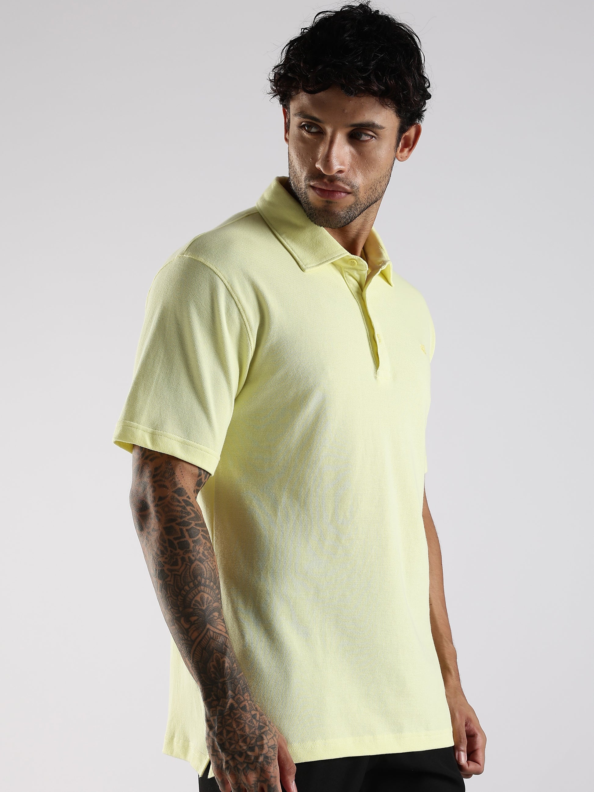 Man wearing a light yellow polo shirt against a plain background