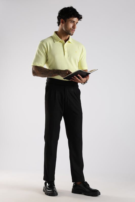 Man wearing a light yellow polo shirt and black pants holding a tablet on a white background